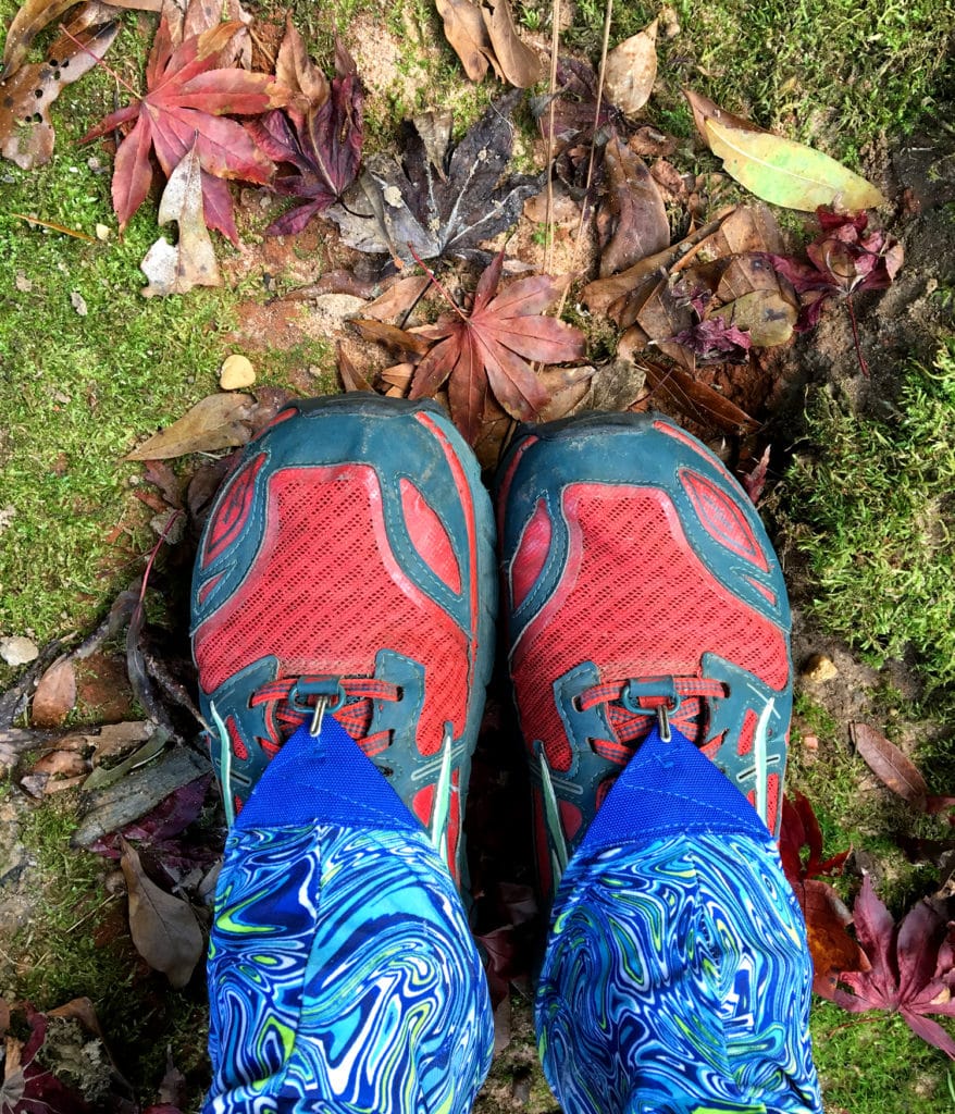 A hiker wears gaiters and trail running shoes while hiking.