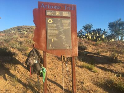 A Arizona trail sign with Legend's backpack hanging off of it