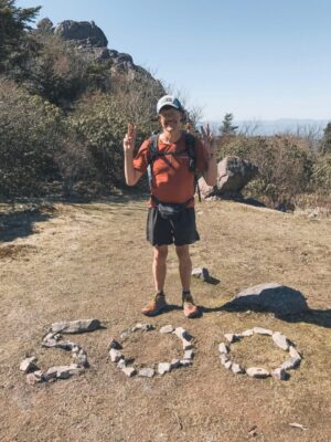 A hiker with rocks at his feet spelling out 500 for 500 miles done on trail