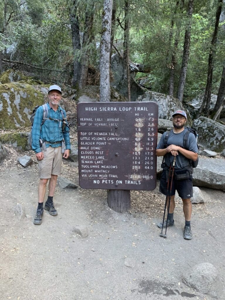 Two hikers standing next to the northern terminus of the John Muir Trail.