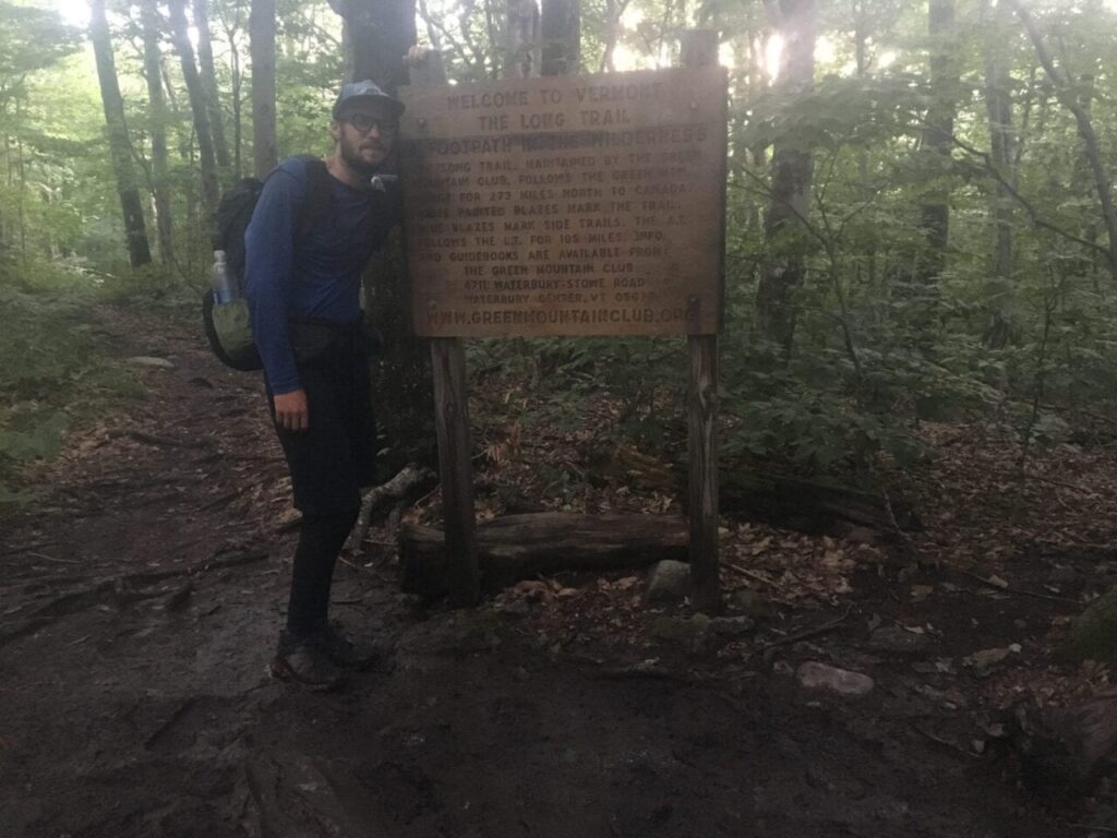 A thru-hiker posing at the end of the Long Trail.