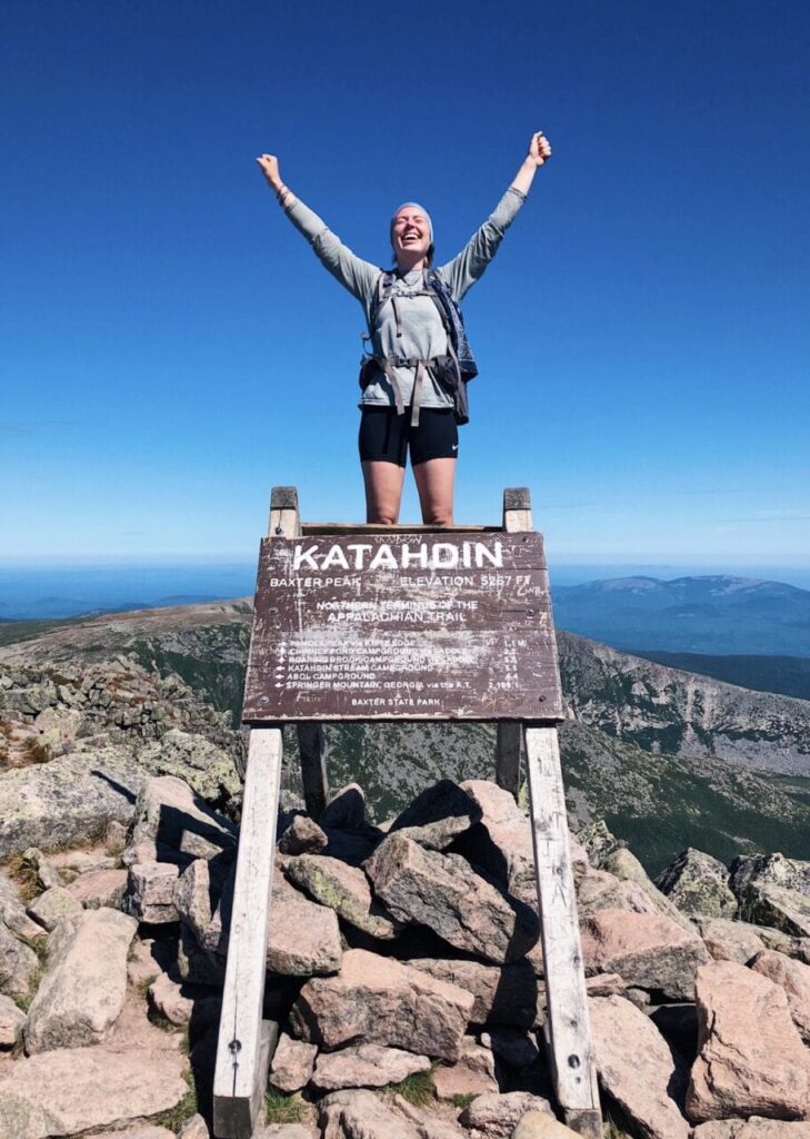 An Appalachian Trail Thru-Hiker celebrating at the northern terminus of the AT.