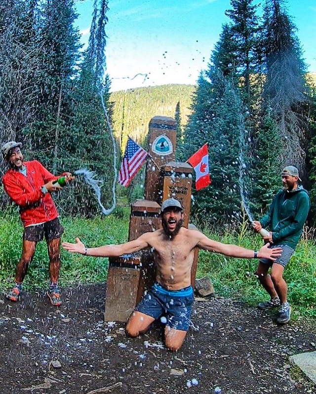 Thru-Hiker Grizzly along with two other thru-hikers celebrating at the northern terminus of the PCT.