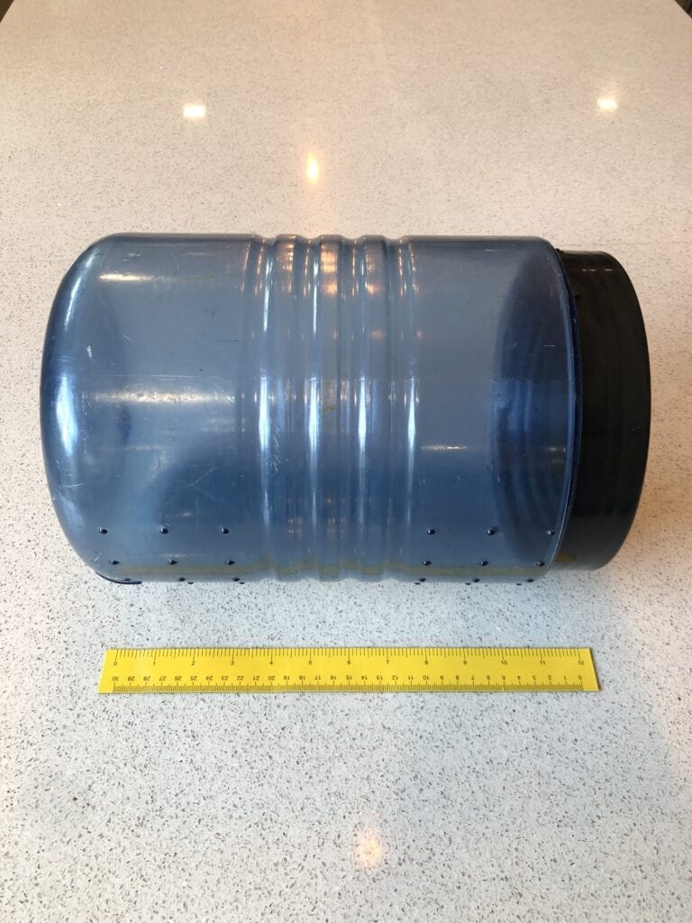 A BV500 bear canister laying down on its side next to a ruler.