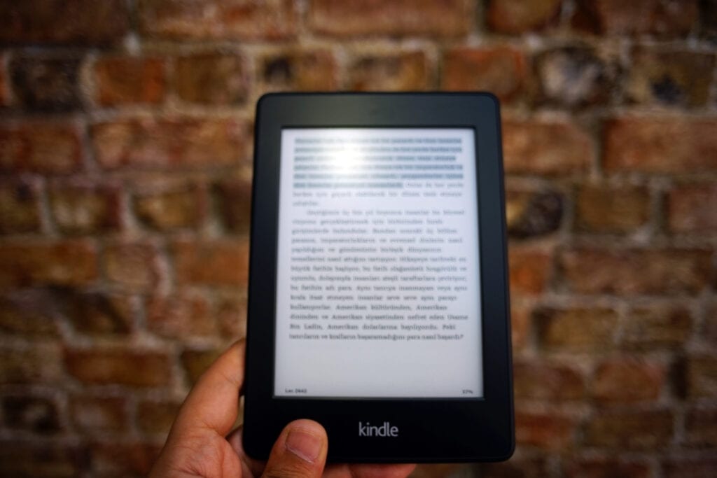A hand holding a kindle. A nice addition to the luxury items for the reader.
