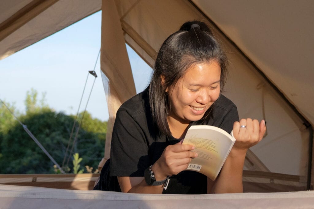 A woman reading a book in a tent.