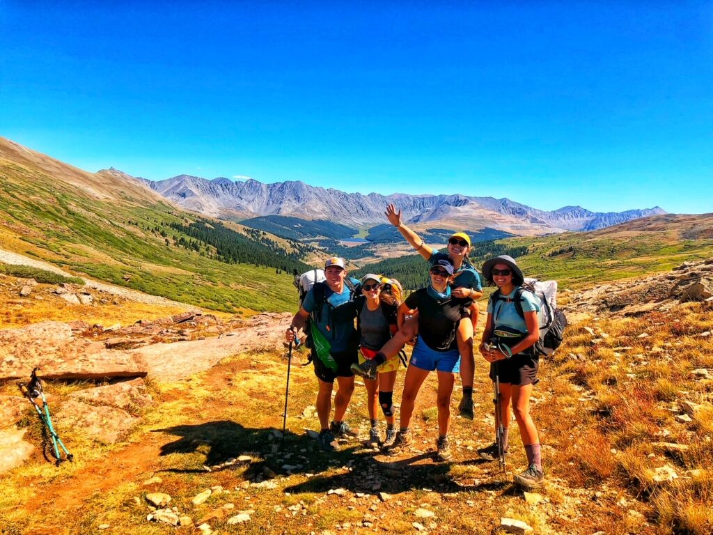 a group of hikers posing on top of a mountain pass with more mountains in the background
