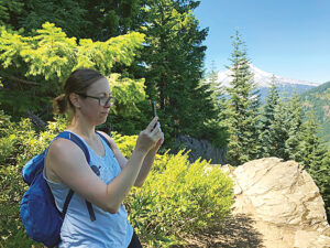 a woman taking a photo on her phone in nature