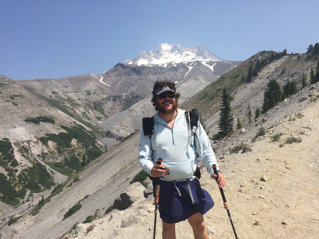 a hiker standing on a mountain side with mountains in the background