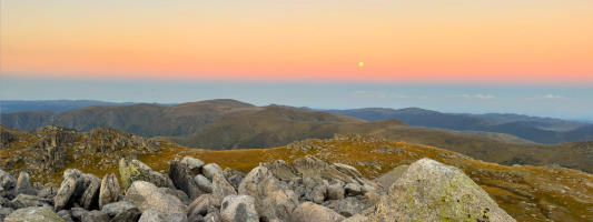 a sunset over some mountain hills