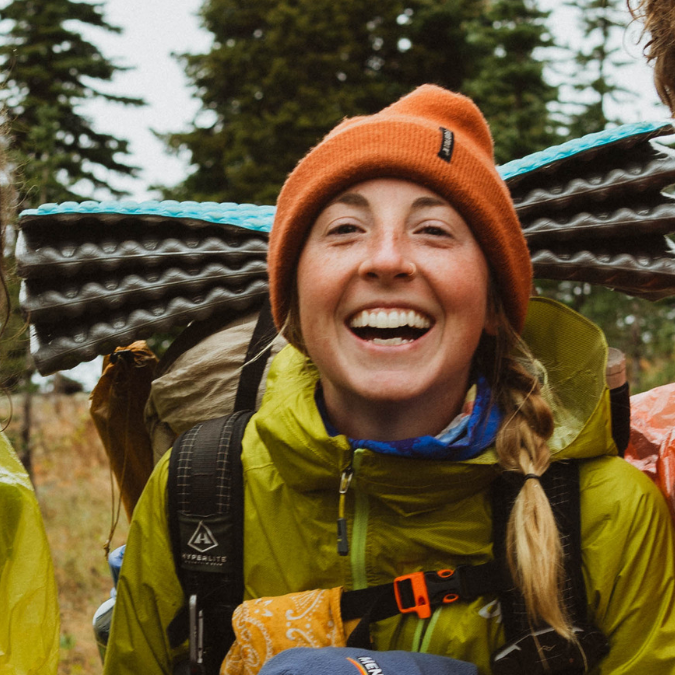 a hiker smiling with a beanie and backpack on