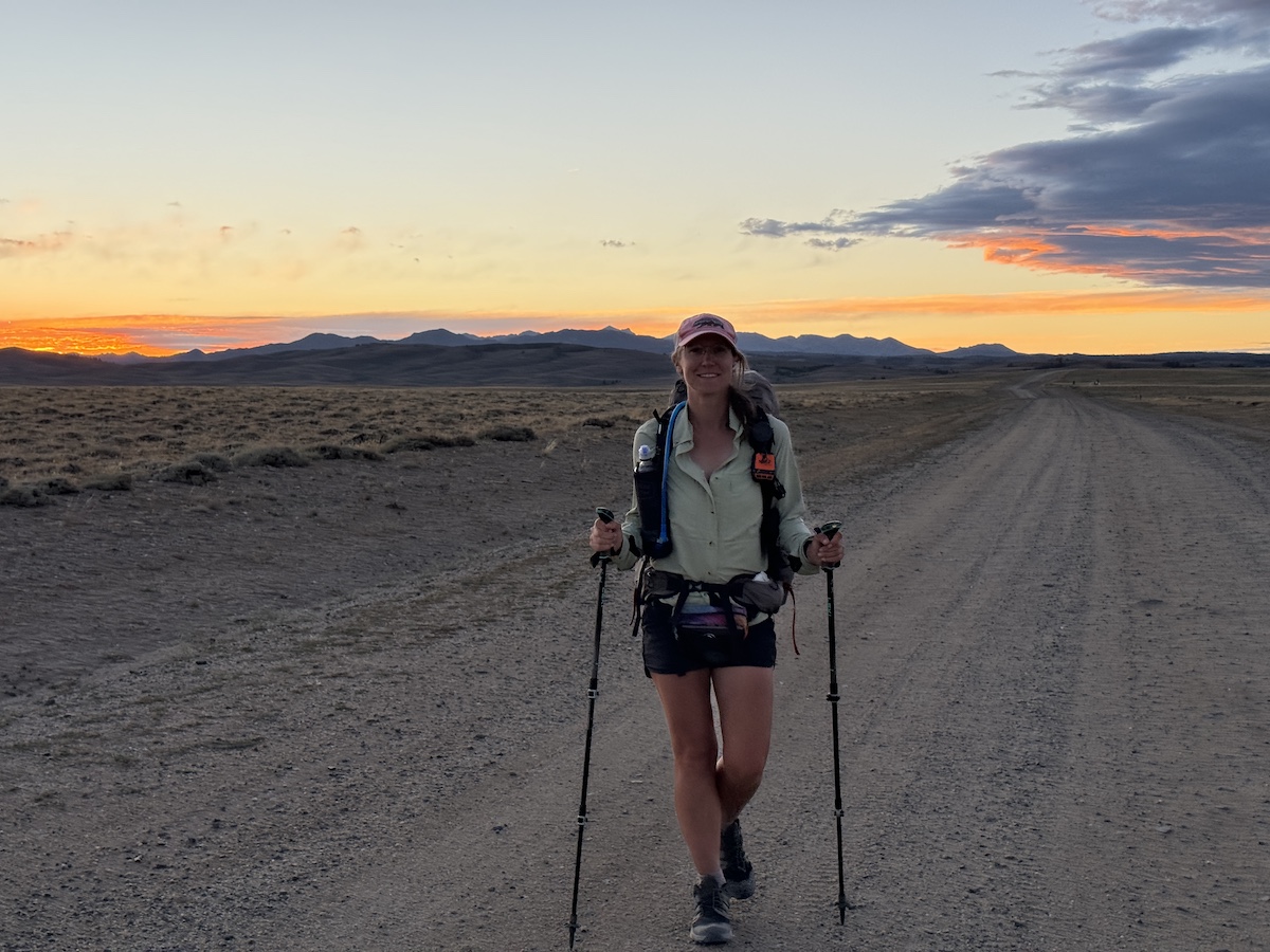 a hiker on a dirt path during sunset