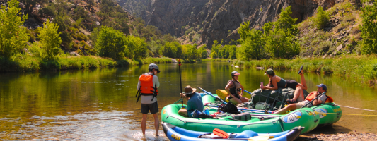 people sitting in rafts on the bank of the Gunnison River