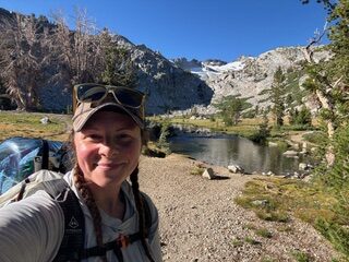 a hiker smiling with a lake and mountains