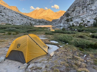 a yellow tent with mountains in the background