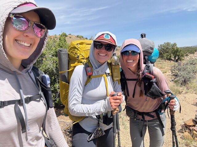 three hikers smiling with backpacks on
