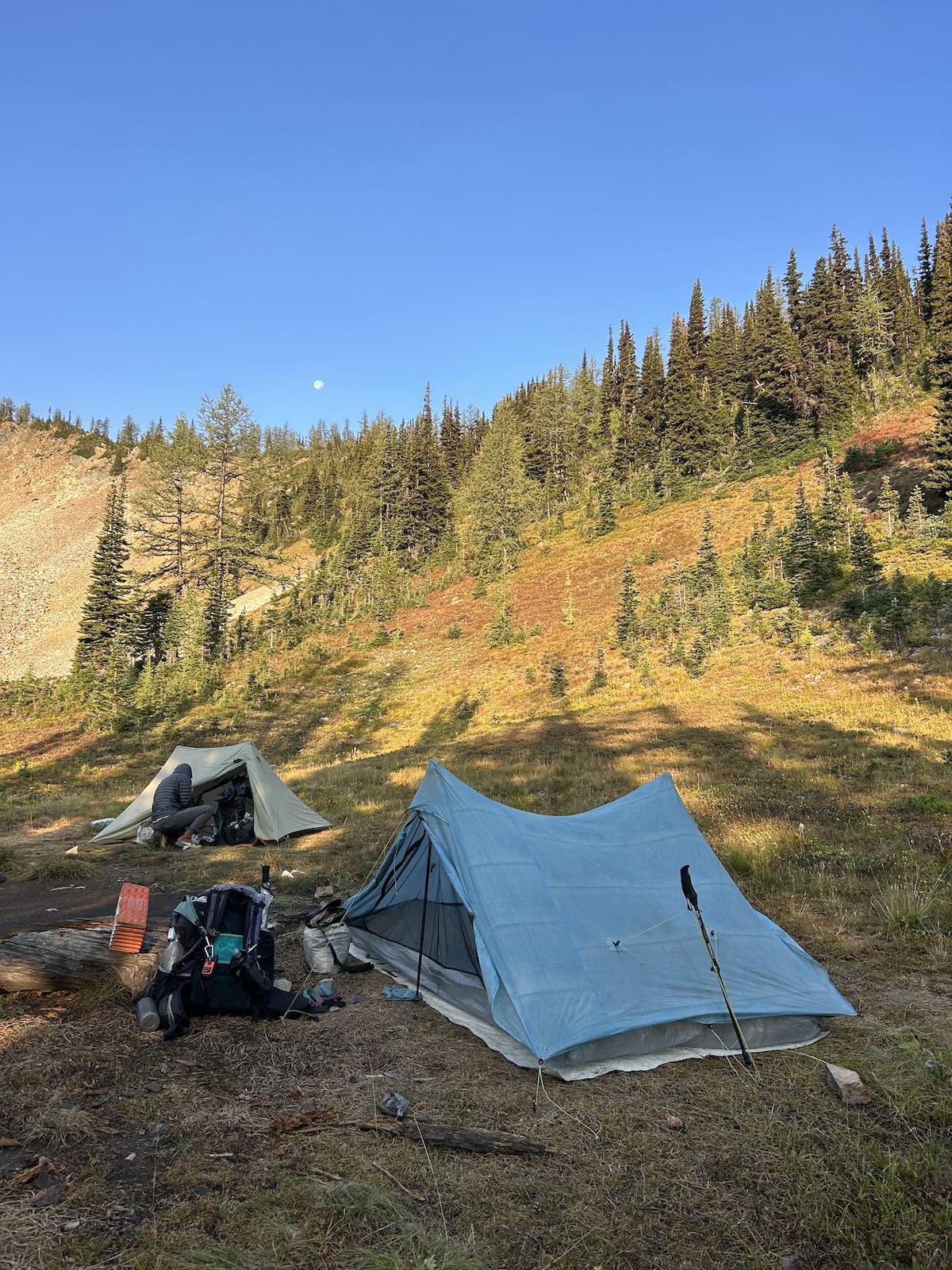 two tents set up at the base of a tree filled mountain