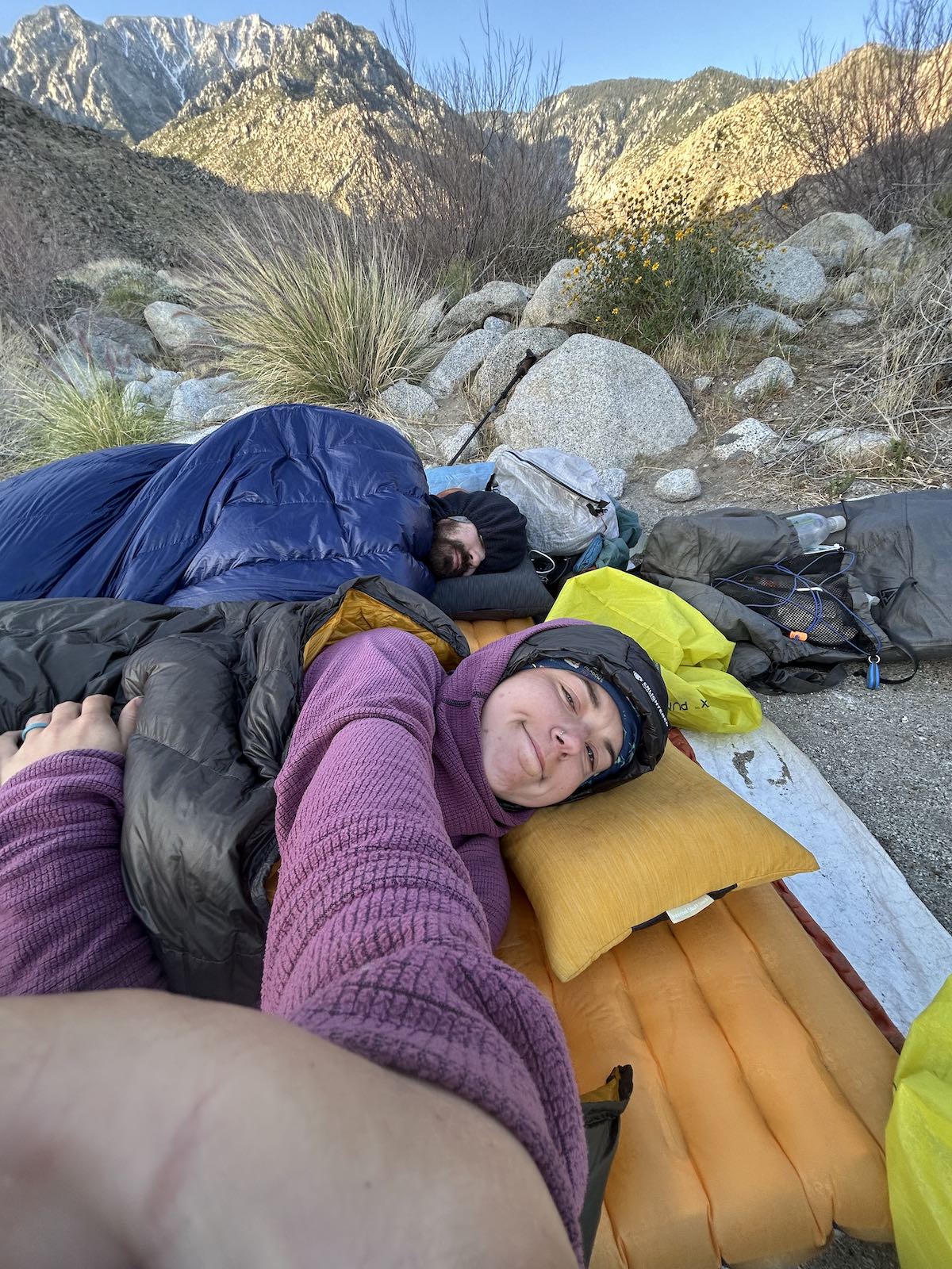 two hikers laying in the sleeping bags cowboy camping