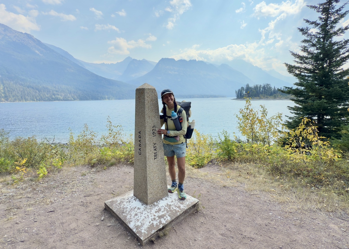 a hiker standing next to the northern terminus of the Continental Divide Trail