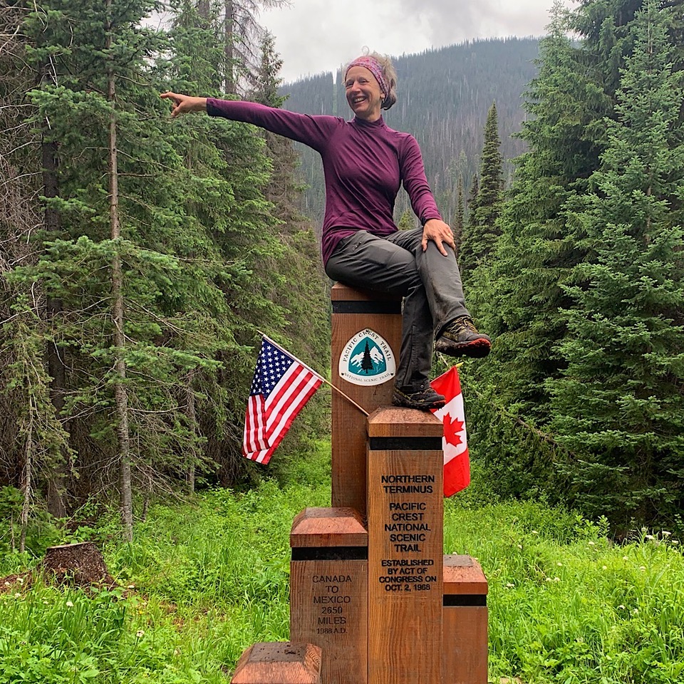 a hiker sitting on top of the PCT northern terminus