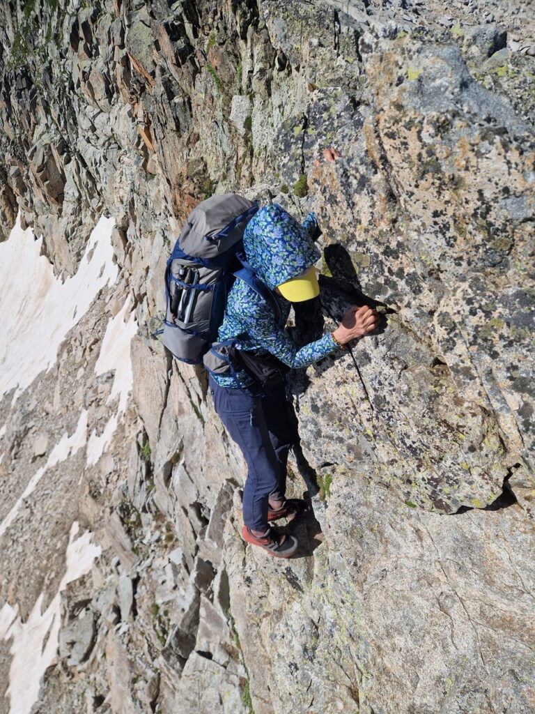 a hiker climbing along a rock wall of a mountain