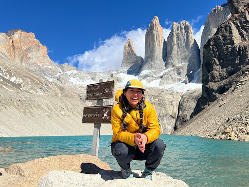 a hiker smiling in front of a lake and mountains on the Torres del Paine