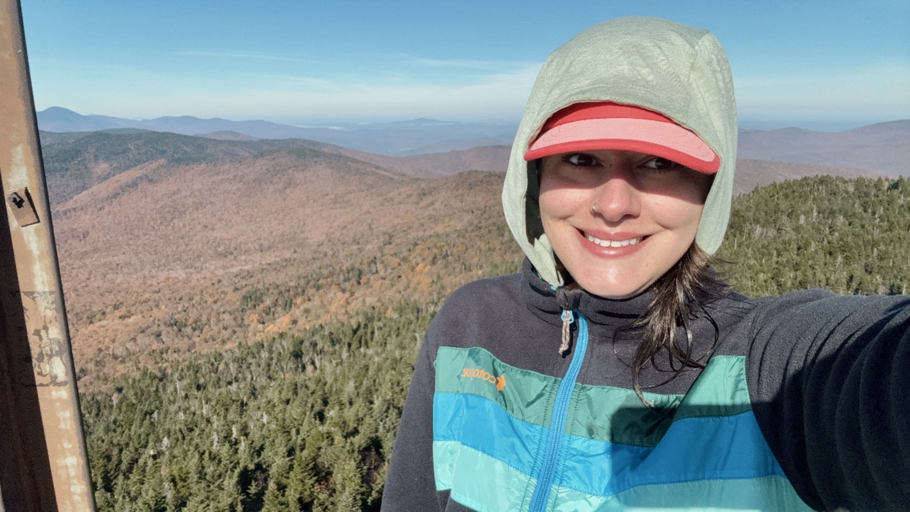 hiker_view a hiker taking a selfie with a view of tree covered hills in the background