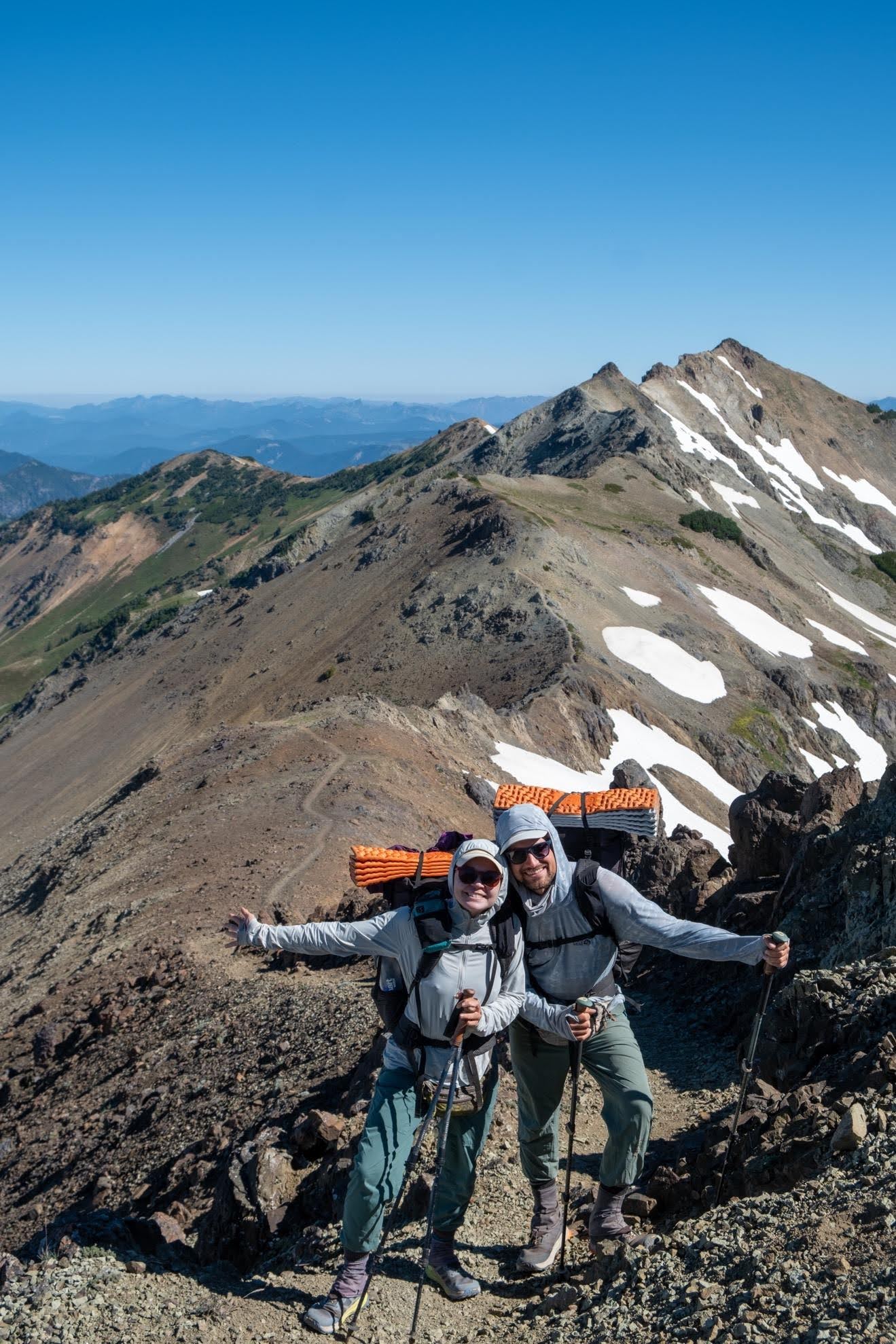 two hikers posing on top of a mountain range